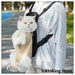 Beige grid cat carrier backpack on city street with Glimbo and Glimby mascots - urban adventure
